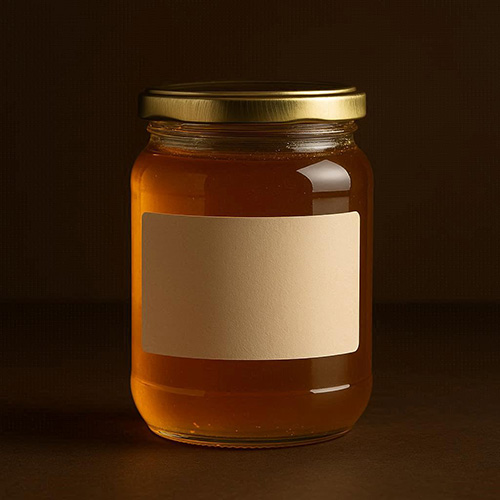 A glass jar of honey sitting on a dark background